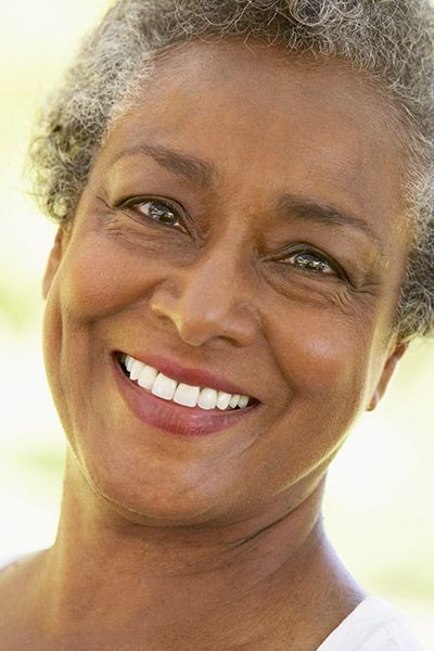 woman showing off her restored smile thanks to dental crowns from Pacific Coast Dentistry