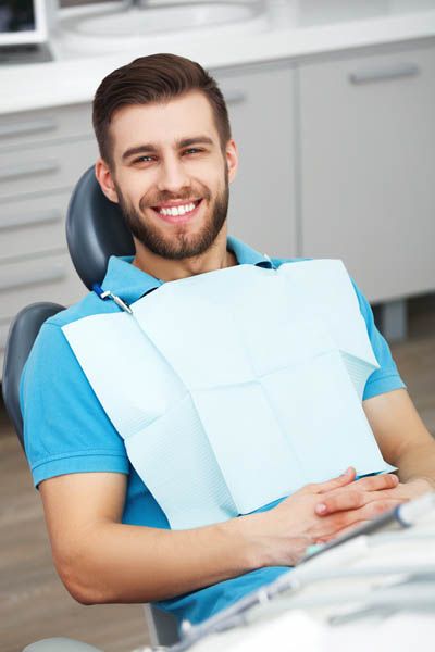 man showing off his smile after getting full-mouth reconstruction from Pacific Coast Dentistry in Paso Robles, CA