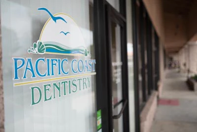 Pacific Coast Dentistry logo hanging on the front window of the office