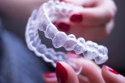 woman holding her new Invisalign clear aligners